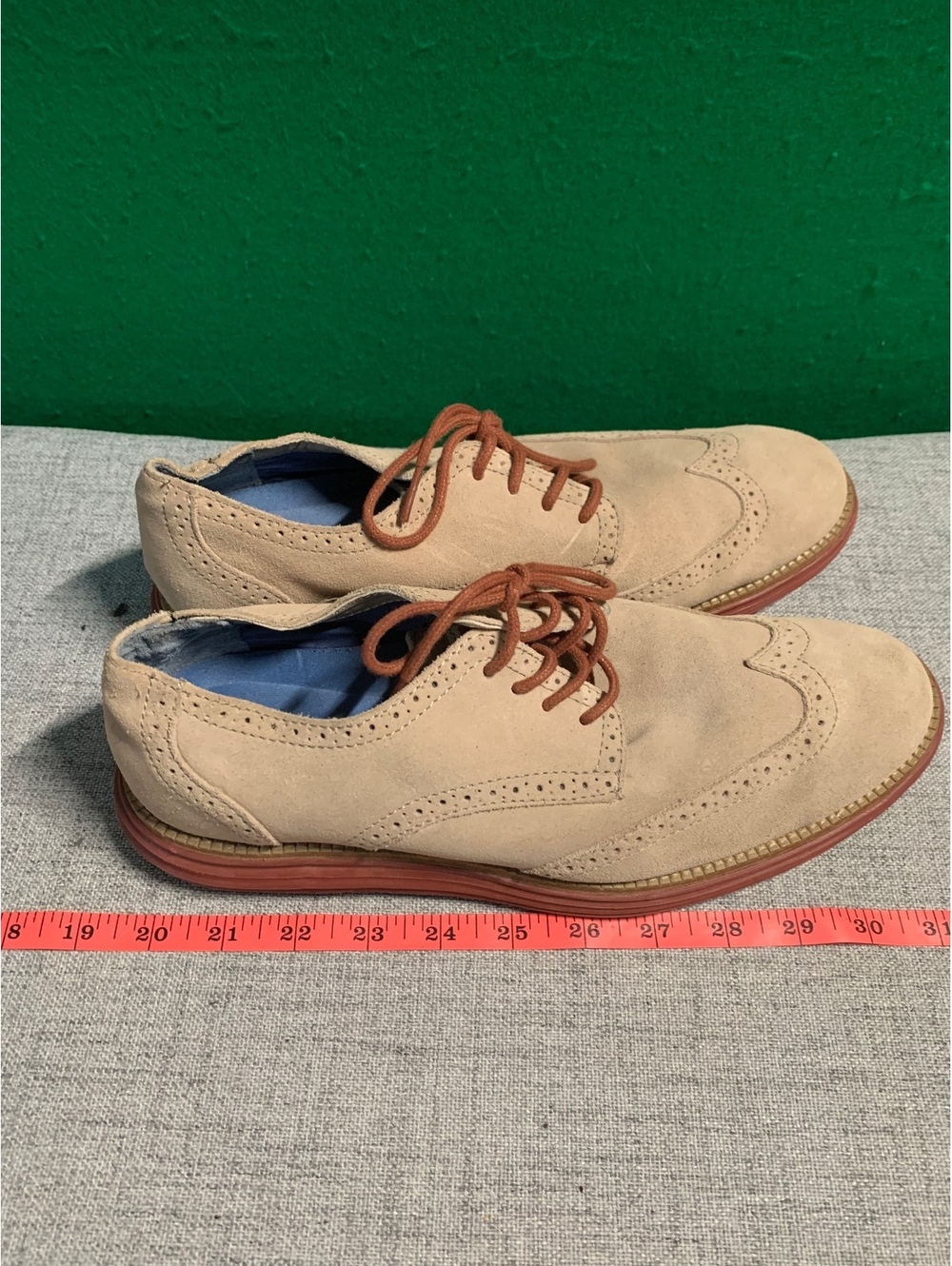 Beige suede wingtip oxford shoes with brick red soles